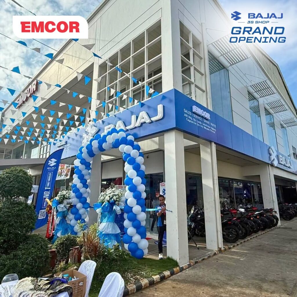 Blue and white Bajaj 3S Shop storefront with an EMCOR sales, service, and spare parts sign and a balloon arch at the entrance