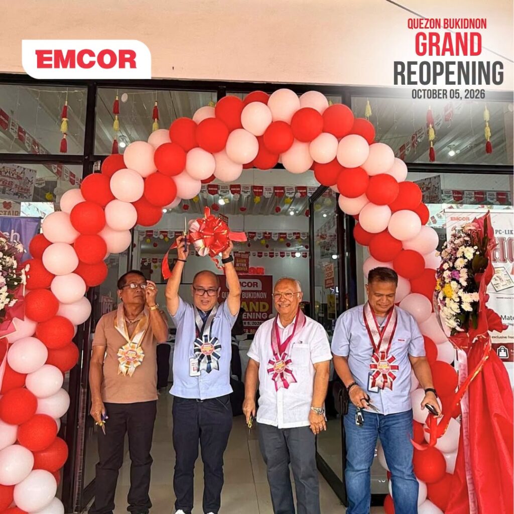 Four guests wearing sashes cut the ceremonial ribbon under a red and white balloon arch at the EMCOR store entrance